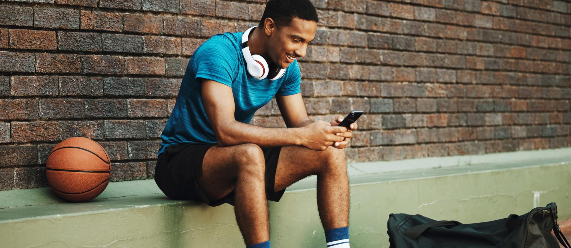 A man next to a basketball court on his phone