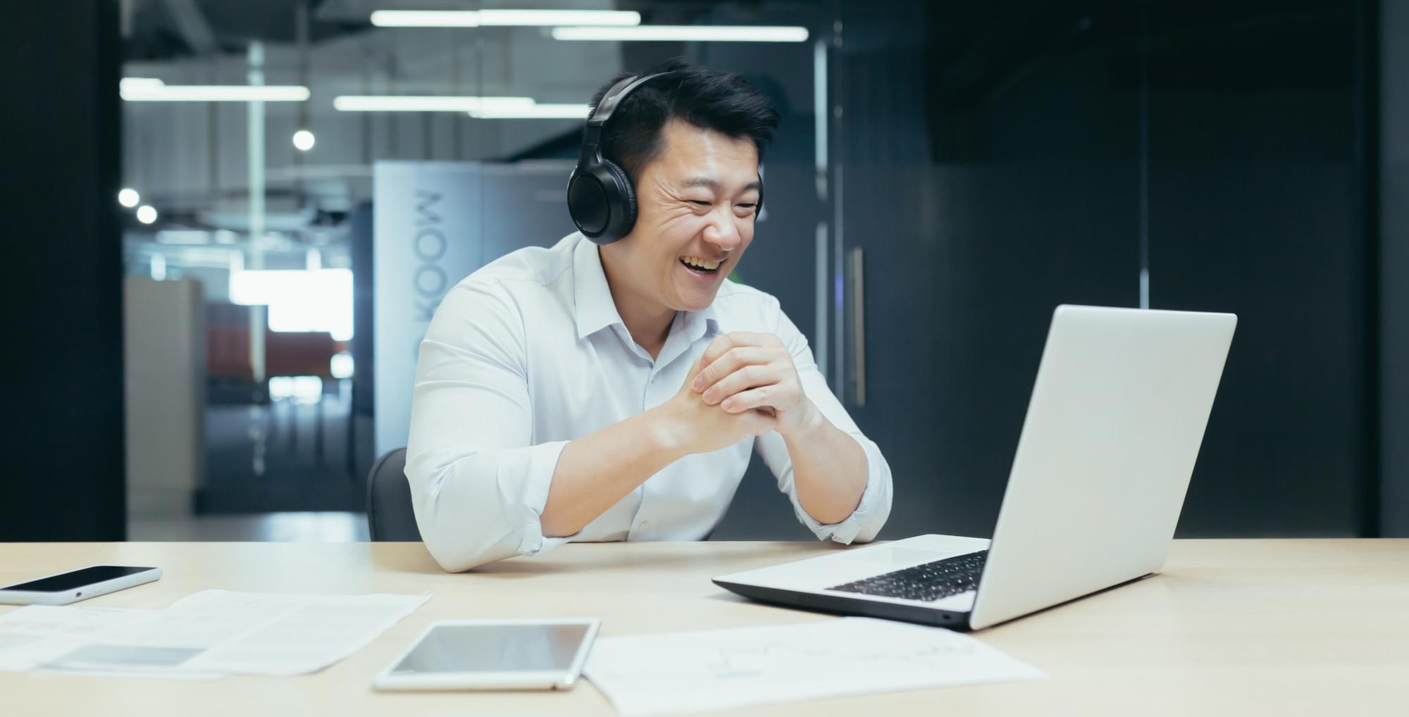 A happy businessman watching a sporting event on his laptop