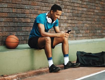 A man next to a basketball court on his phone