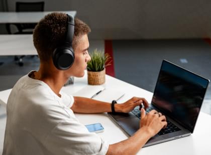 A young man with headphones on his laptop