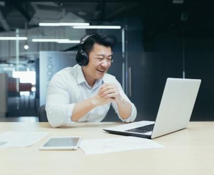 A happy businessman watching a sporting event on his laptop