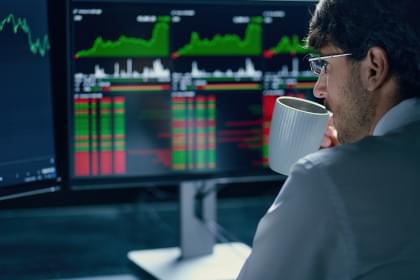 A sports betting investor analyzing data and drinking coffee